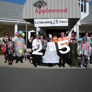 A group of people gathered in front of Applewood, celebrating its 25th anniversary.