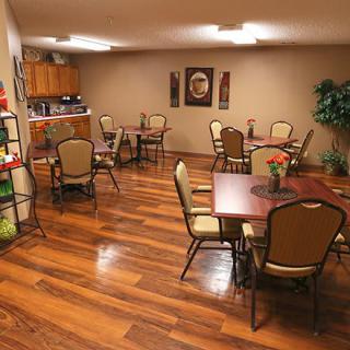 A cozy dining area with hardwood floors, tables, and chairs, featuring decorative artwork on the walls.