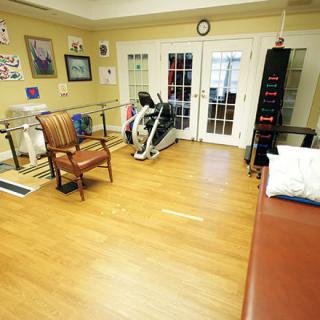 A rehabilitation room equipped with exercise machines and seating, designed for physical therapy sessions.