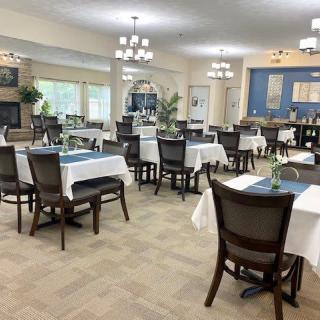 An elegant dining room setup with neatly arranged tables and chairs, featuring chandeliers and tasteful decor.