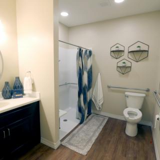 A modern bathroom with a shower, toilet, and sink, featuring decorative elements and warm lighting.