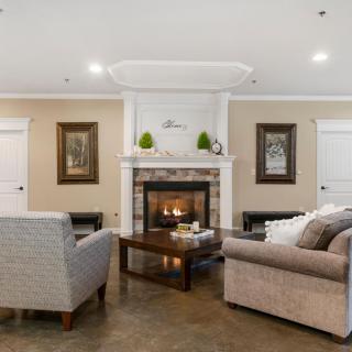 A cozy living room with a central fireplace surrounded by comfortable seating and tasteful decor.