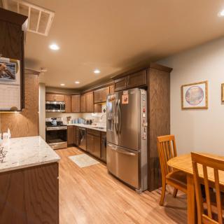 A modern kitchen with wood cabinets, stainless steel appliances, and a small dining area.