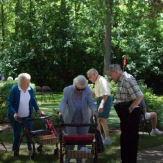 A group of seniors enjoying a day outdoors in a park with walkers.