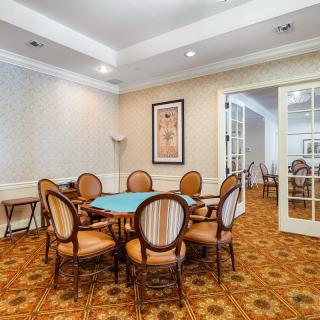 A cozy dining or meeting room with a round table and six chairs, set on a patterned carpet.