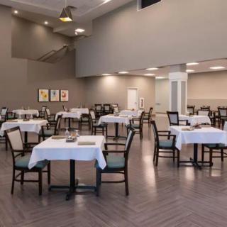 An empty dining area with neatly arranged tables covered in white tablecloths.