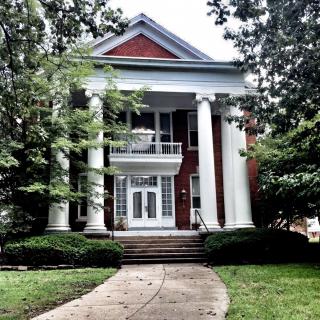 A historic house with large columns and a well-maintained lawn.