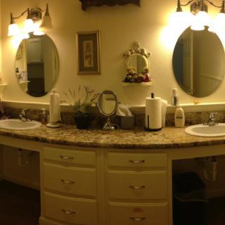 A well-lit bathroom with a double vanity and oval mirrors.