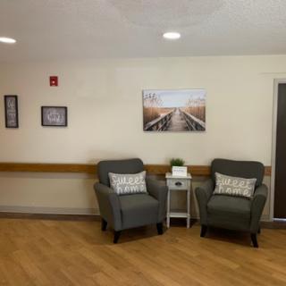 A cozy waiting area featuring comfortable chairs, decorative wall art, and warm lighting.