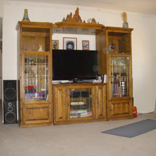A wooden entertainment center with a television and shelves in a living room setting.