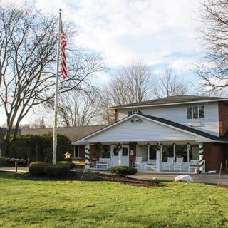 A two-story house with a front porch and an American flag flying in the yard.