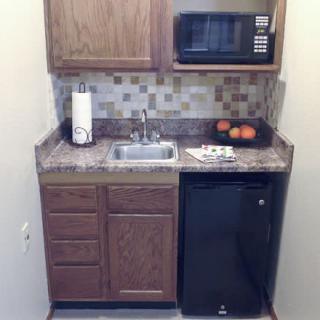 Cozy kitchenette with a microwave, mini fridge, and sink.
