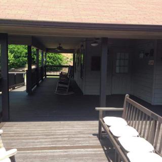 A covered porch with wooden benches and a deck in the sunlight.