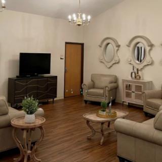 A cozy living room with beige sofas, decorative mirrors, and a television.