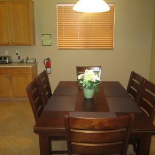 A cozy dining area with a wooden table and chairs, adorned with a flower centerpiece.