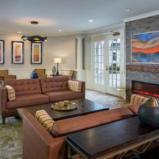 A stylish and cozy living room featuring a sofa, coffee table, and a fireplace adorned with artwork.