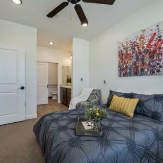A modern and cozy bedroom with colorful artwork above the bed and soft lighting.
