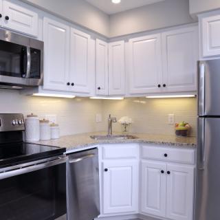 A modern kitchen with white cabinets and stainless steel appliances.
