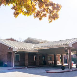 A welcoming entrance of a modern red brick building, surrounded by trees on a sunny day.