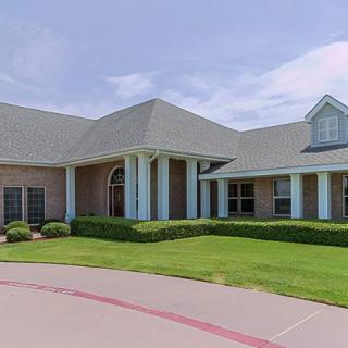 A suburban house with a well-maintained lawn and prominent columns at the entrance.