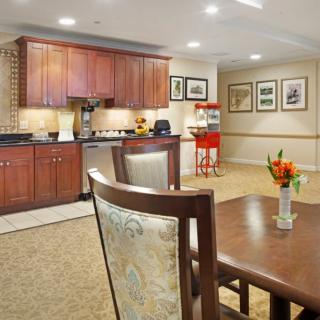 A cozy kitchen and dining area featuring wooden cabinets, a countertop, and a vase with flowers on the table.