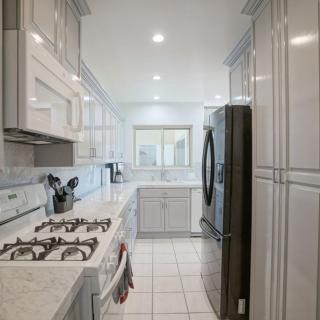 A modern kitchen with white cabinetry and a stainless steel refrigerator.