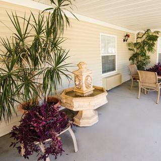 A cozy outdoor patio with lush plants, a decorative fountain, and seating area.