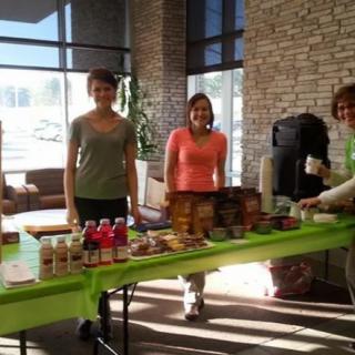 A group of people standing behind a table with food and drinks at an indoor event.