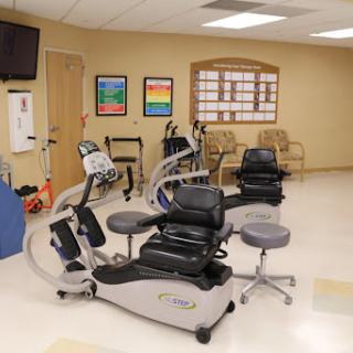 A well-equipped rehabilitation room featuring various exercise machines and seating arrangements for patients.