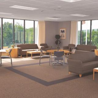 A spacious and comfortable waiting room with sofas, chairs, and tables arranged near large windows.