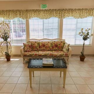 A cozy living room with floral furniture and large windows.
