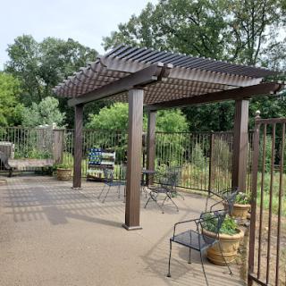 A serene outdoor patio area featuring a pergola, seating arrangements, and lush greenery.