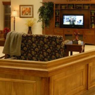 A cozy living room with a floral-patterned couch facing a wooden entertainment center and television.