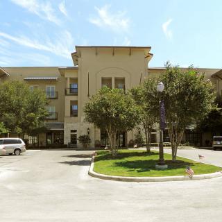 A residential building with a parking area and trees on a sunny day.