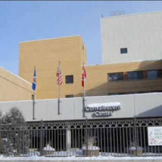 A view of a healthcare facility featuring multiple flags and signage, set against a snowy backdrop.