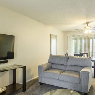A modern living room with a sofa, TV, and glass table.