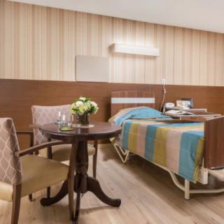 A well-furnished hospital room with a bed, table, and chairs.