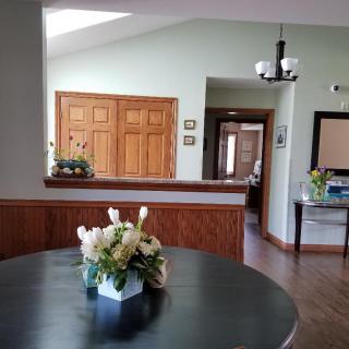 A cozy living area featuring a round table with a floral centerpiece, wooden doors, and soft lighting.