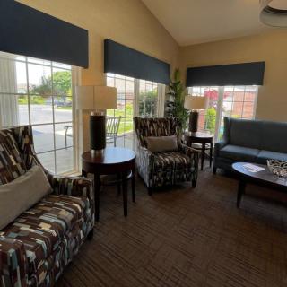 A cozy living room with patterned chairs, a sofa, and large windows allowing natural light.