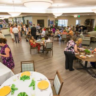 A social gathering taking place in an indoor dining area with people interacting at various tables.