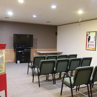 A cozy home theater setup with a row of chairs facing a large TV, accompanied by a popcorn machine.