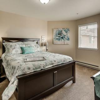 A cozy bedroom with a neatly made bed, featuring floral bedding and a matching artwork on the wall.