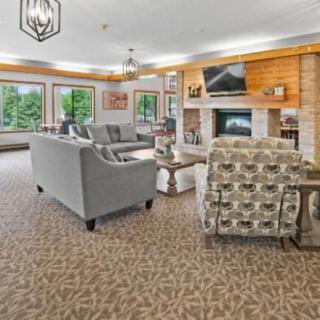 A cozy living room with comfortable seating, a fireplace, and large windows offering natural light.