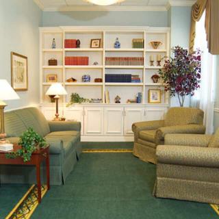 A cozy living room featuring a plush sofa and armchairs, with a bookshelf along the back wall.