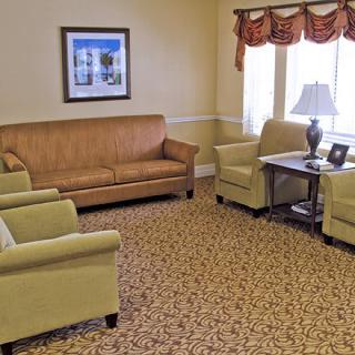 A cozy living room with a sofa, armchairs, and a table under a window.