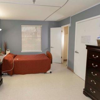 A neatly arranged bedroom with a single bed, dresser, and a window.