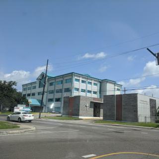A modern building situated at the corner of a street, with a clear blue sky in the background.