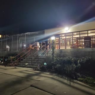A well-lit building at night, featuring stairs and surrounding greenery.