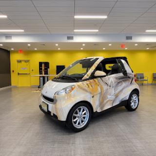A creatively designed smart car displayed in a bright yellow interior space.