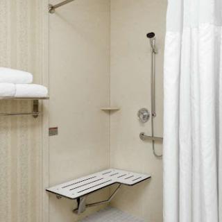 A clean and accessible shower area equipped with a folding bench and neatly arranged towels.